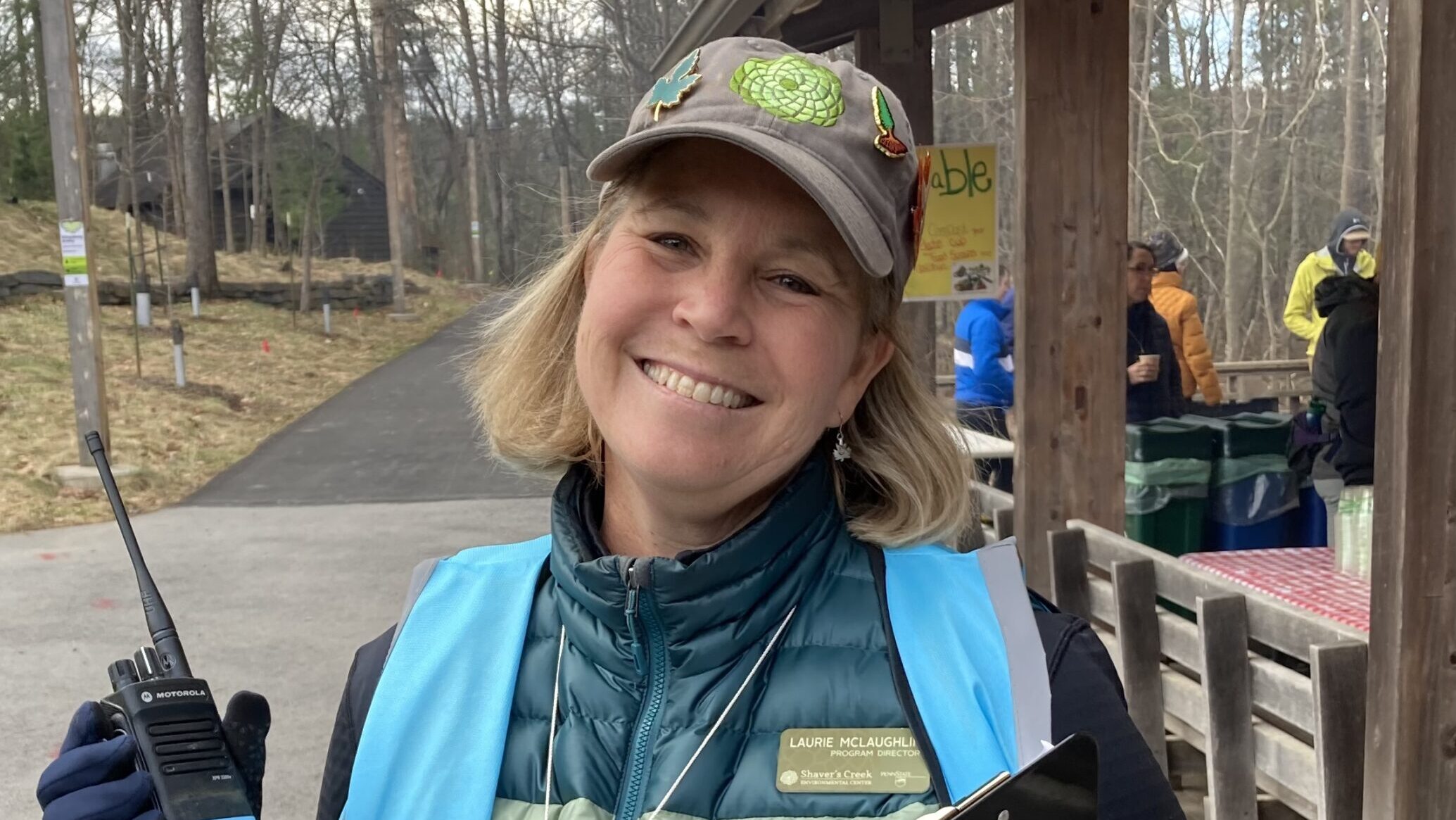 Laurie wearing a Shaver's Creek baseball cap and holding a walkie talkie.