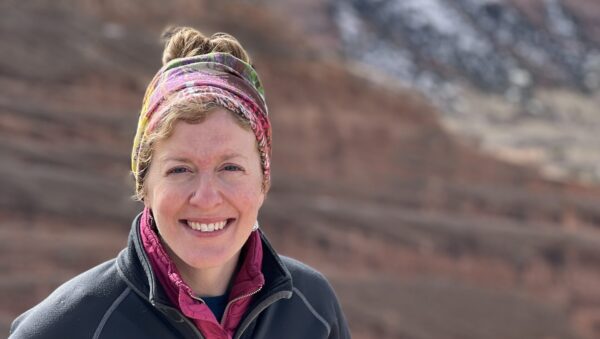 Sarah Potter standing in front of a ridge dappled with snow.