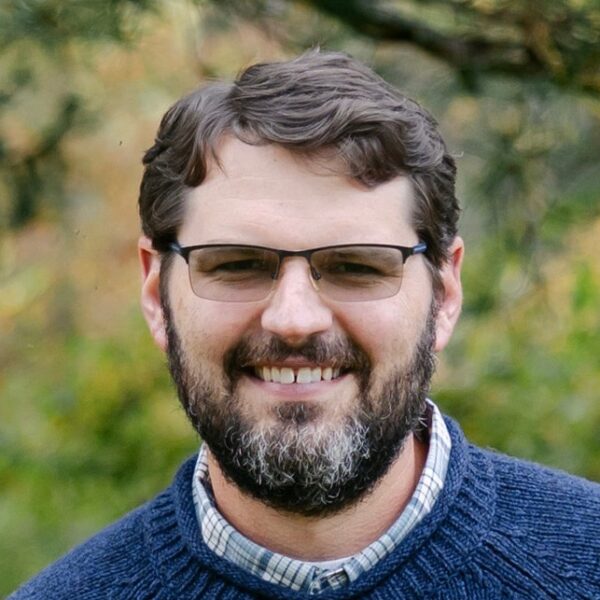 Brian wearing a navy blue sweater and glasses.