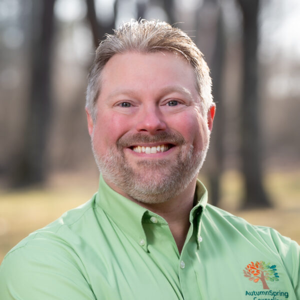 Joshua wearing a green polo shirt with his counseling business logo, AutumnSpring, on the front.