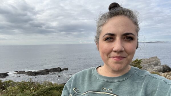 Kristen standing on the shore of a still body of water.
