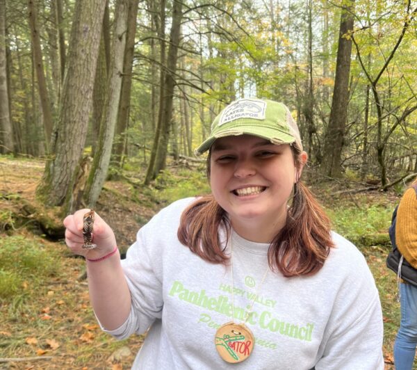 Lydia holding a crayfish in one hand while posing for a picture.