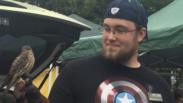 Gabe, wearing a Captain America t-shirt with a small raptor perched on his gloved hand.