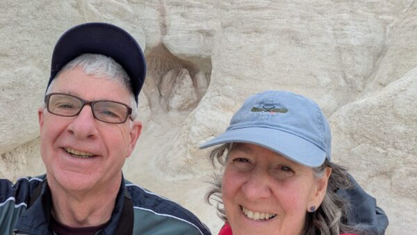 Rebecca and her husband post in front of desert cliffs.