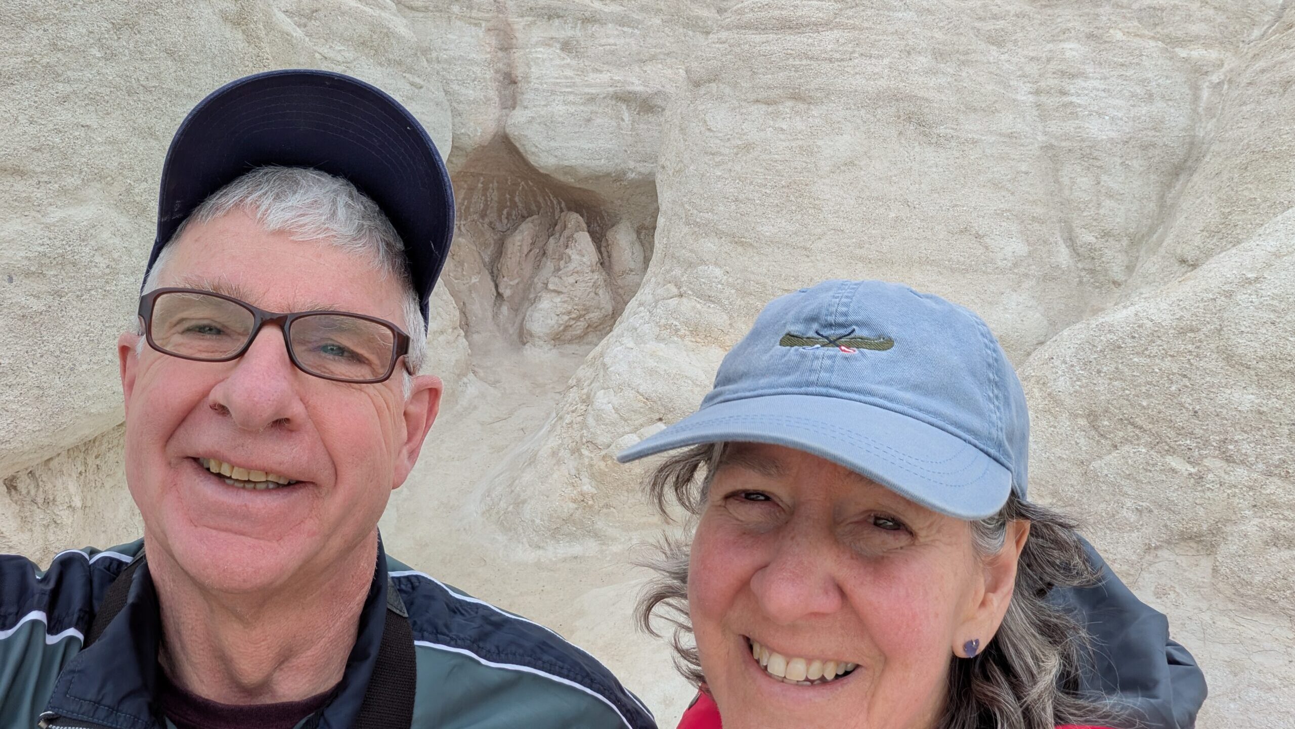 Rebecca and her husband post in front of desert cliffs.