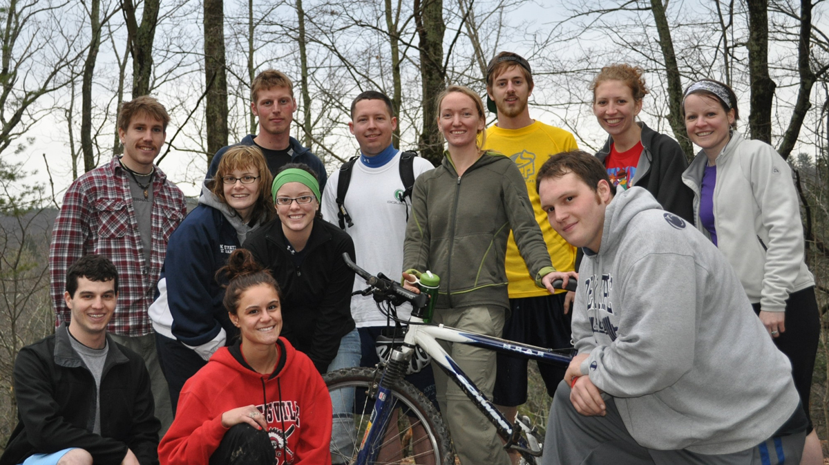 A group of Penn State students stand around a bike