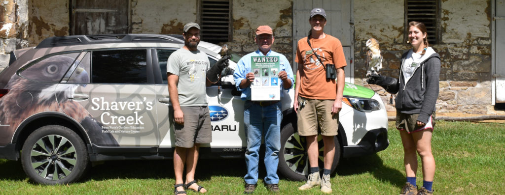Farmland Conservation volunteers pose with a barn owl in front of the Shaver's Creek Subaru