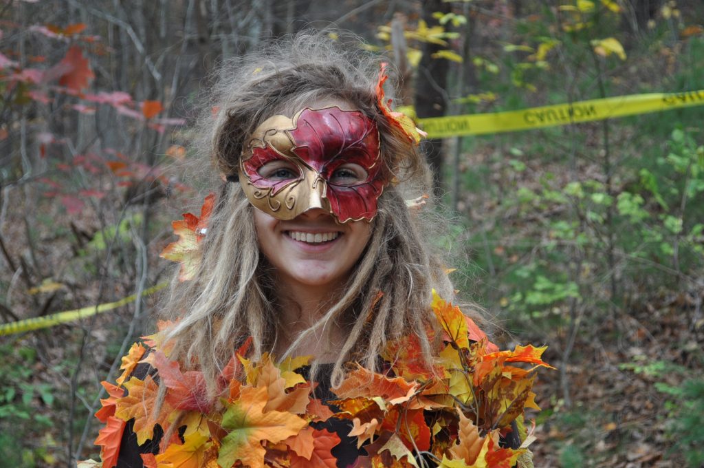 A woman in a mask and a colorful, leafy costume