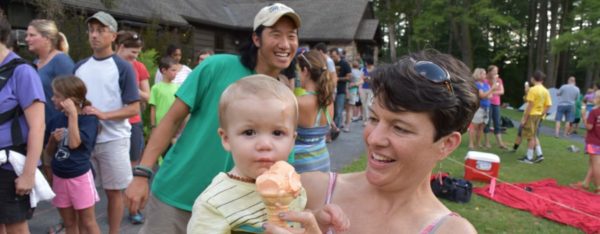 A toddler's mom helps him eat an ice cream cone during a Shaver's Creek event