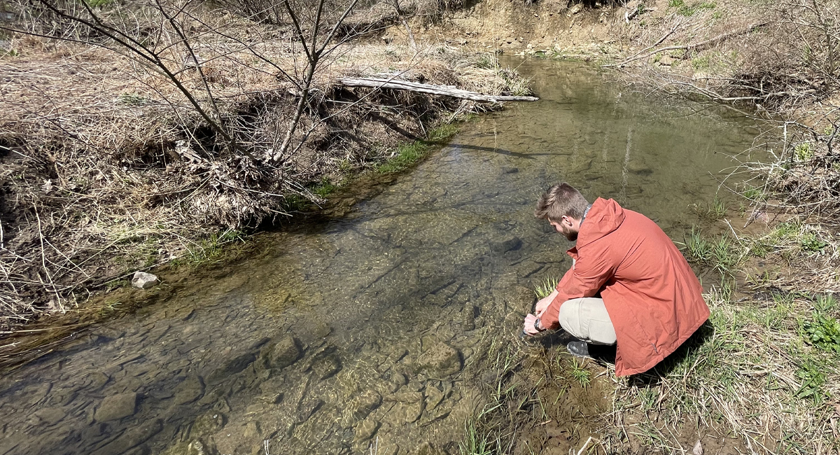 A man taking a water sample from a stream