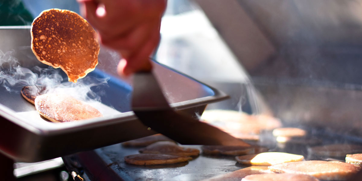 Hot pancakes flipping off the grill