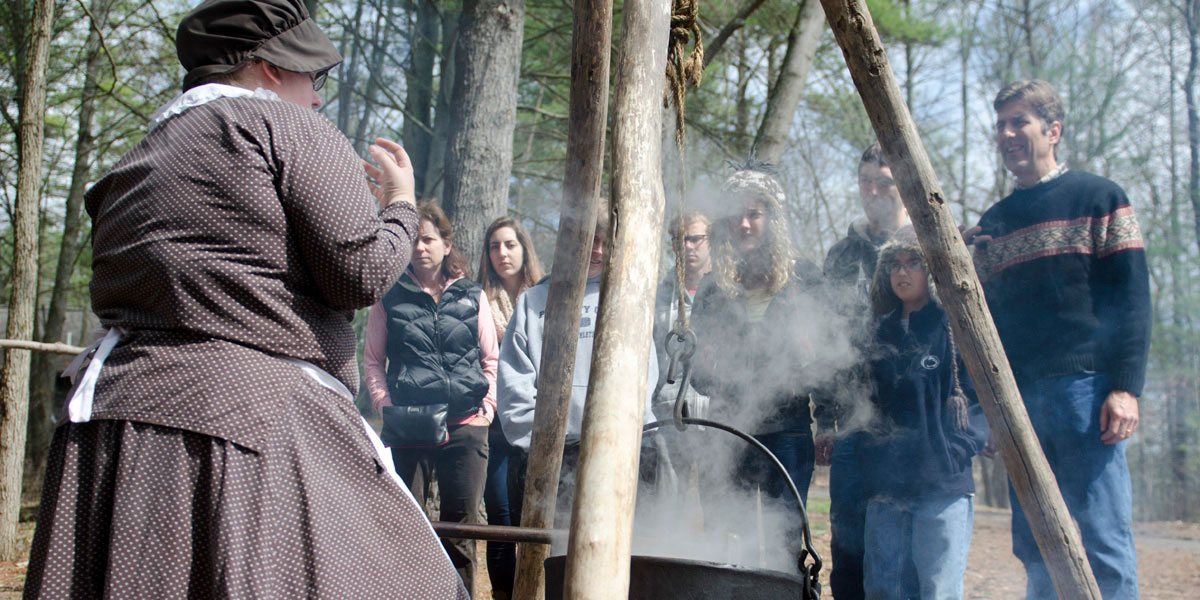 A costumed interpreter demonstrate boiling sap