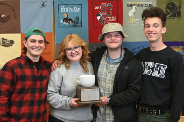 Four people holding the Potter Mug Trophy
