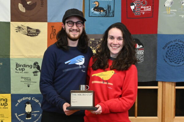 Two people holding the Micro Cup trophy