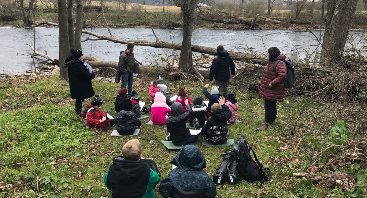 Children learning near a stream.