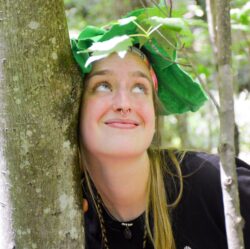 Lexi Arnold smiling among green tree leaves