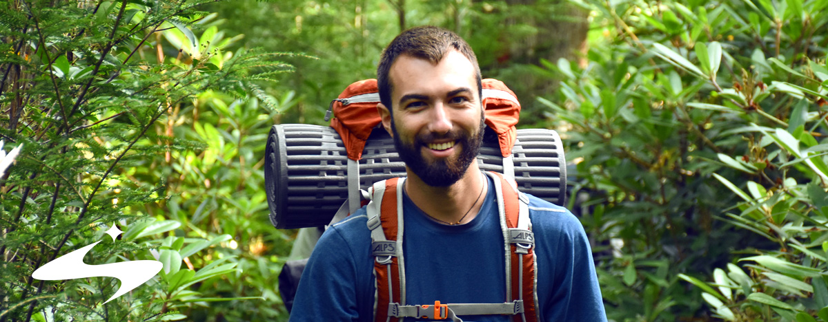 A backpacker walking through a summer forest