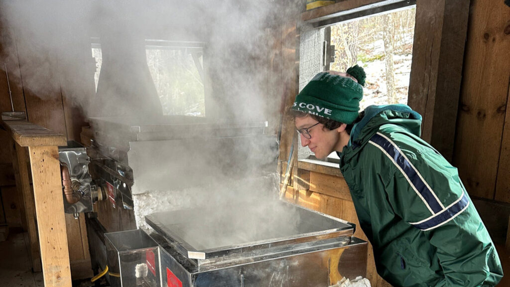 The author stands over a steaming batch of maple sap that is being boiled into maple syrup