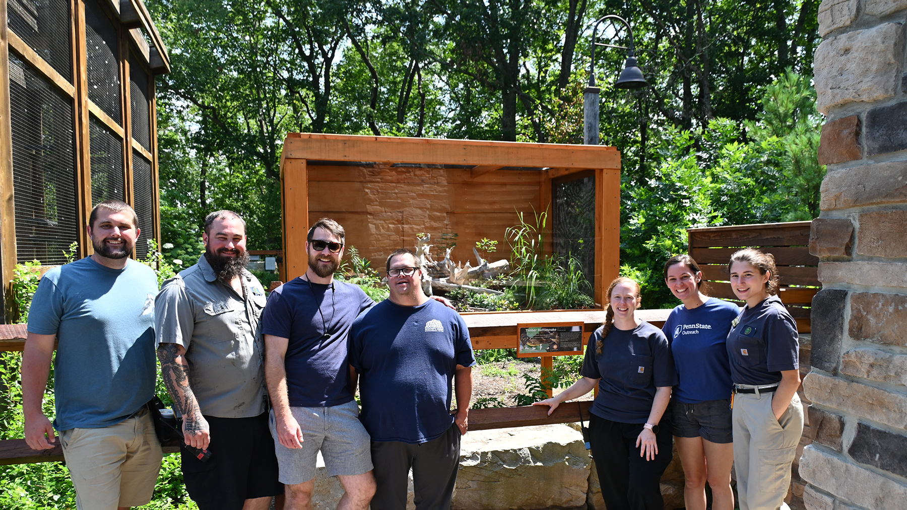 A group of people pose in front of the new Window into the Ridgetops exhibit at Shaver's Creek
