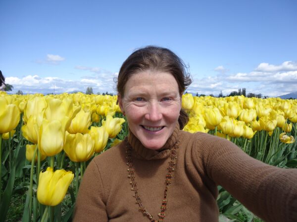 Erin standing in a field of yellow tulips.