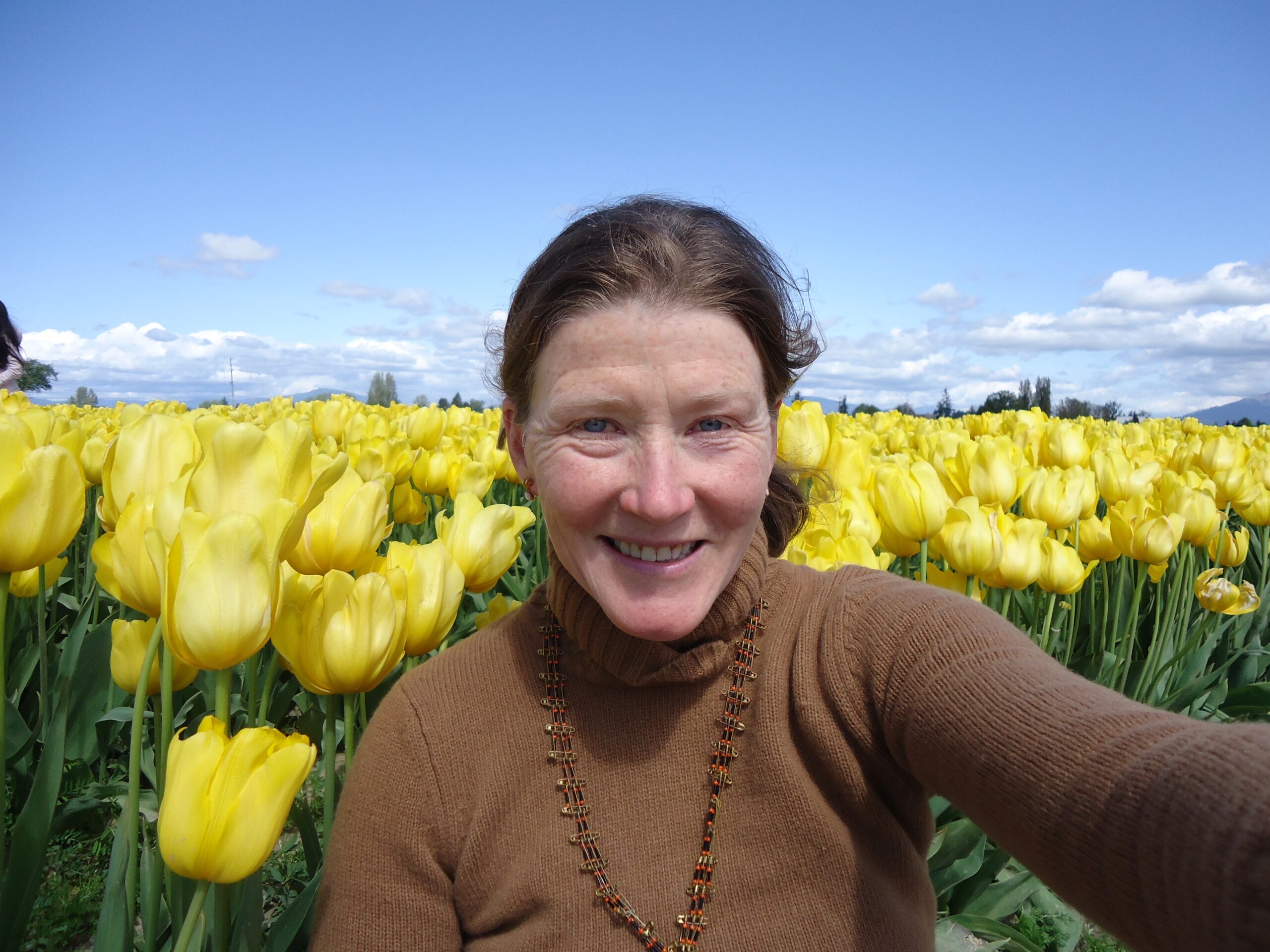 Erin standing in a field of yellow tulips.