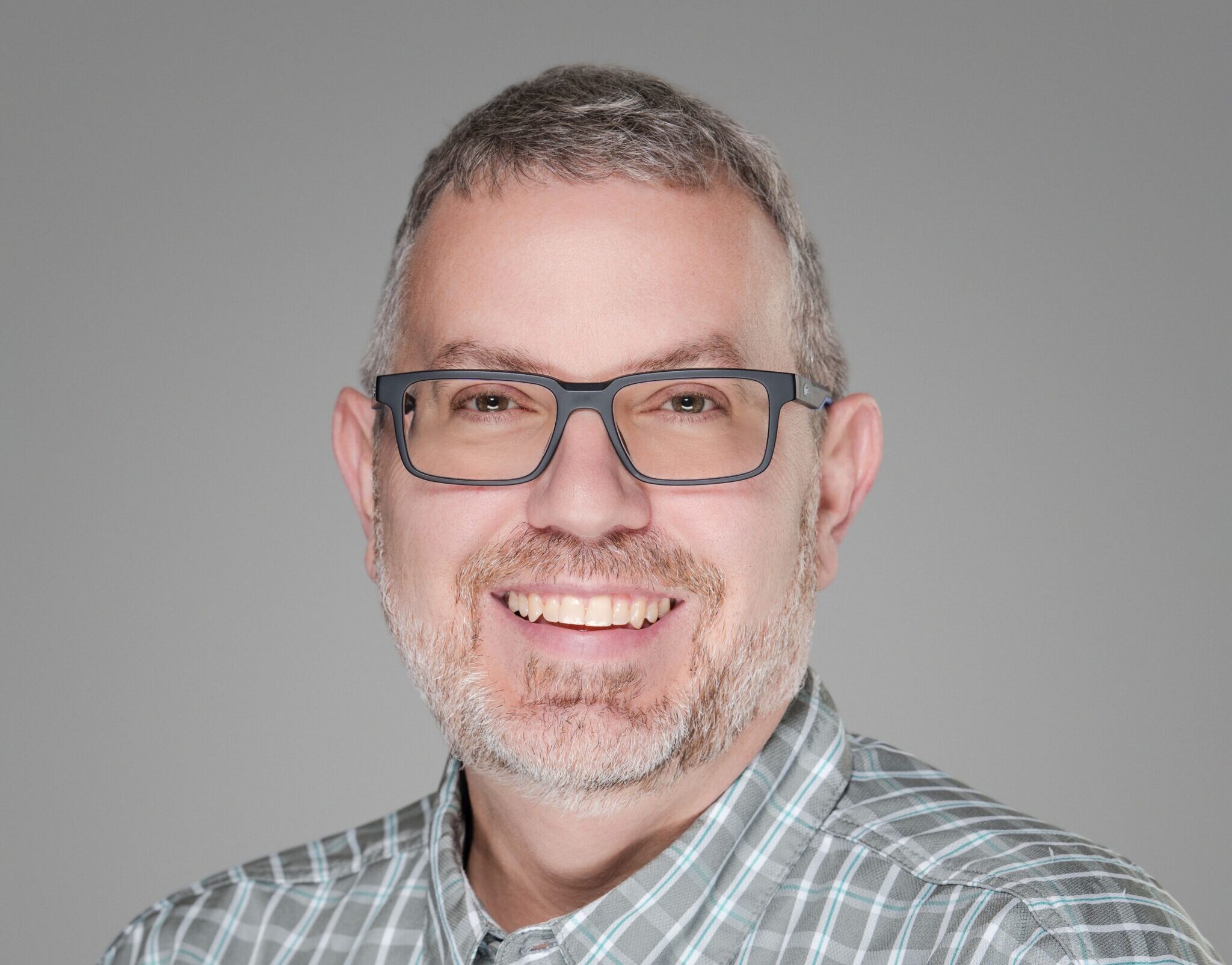 John, wearing a button-down shirt and smiling for a professional photo.
