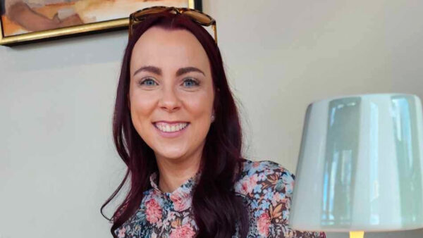 Caitlin smiling and wearing a pair of sunglasses on her head.