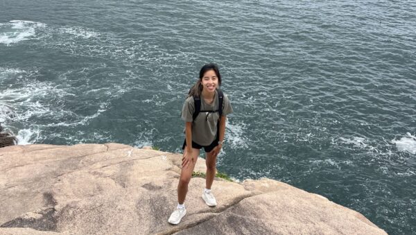 Lydia standing on a rock at the edge of a large body of water.