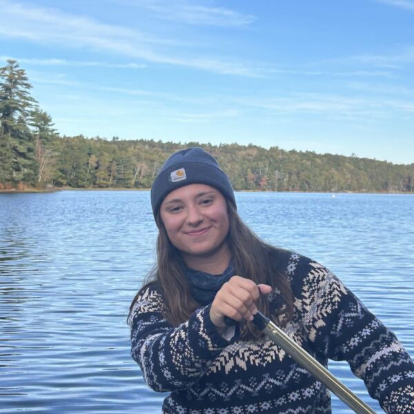 Amy paddling a canoe on a calm body of water.