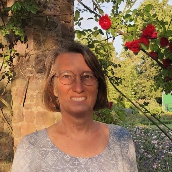 Wibke standing in front of a rose bush.