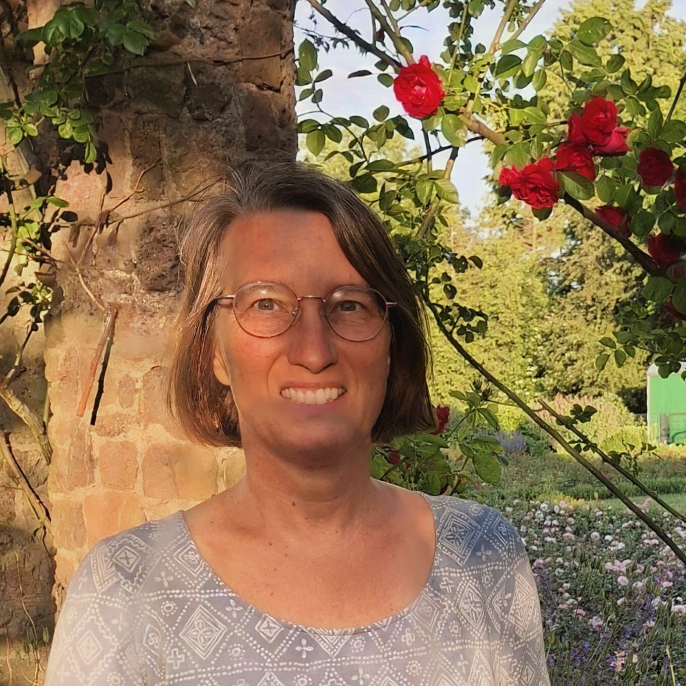Wibke standing in front of a rose bush.