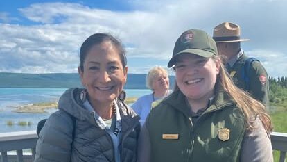 Sarah Bruce posing with Secretary Deb Haaland in front of a lake