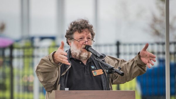 Wes standing at a podium in front of an autumn display of mums and pumpkins