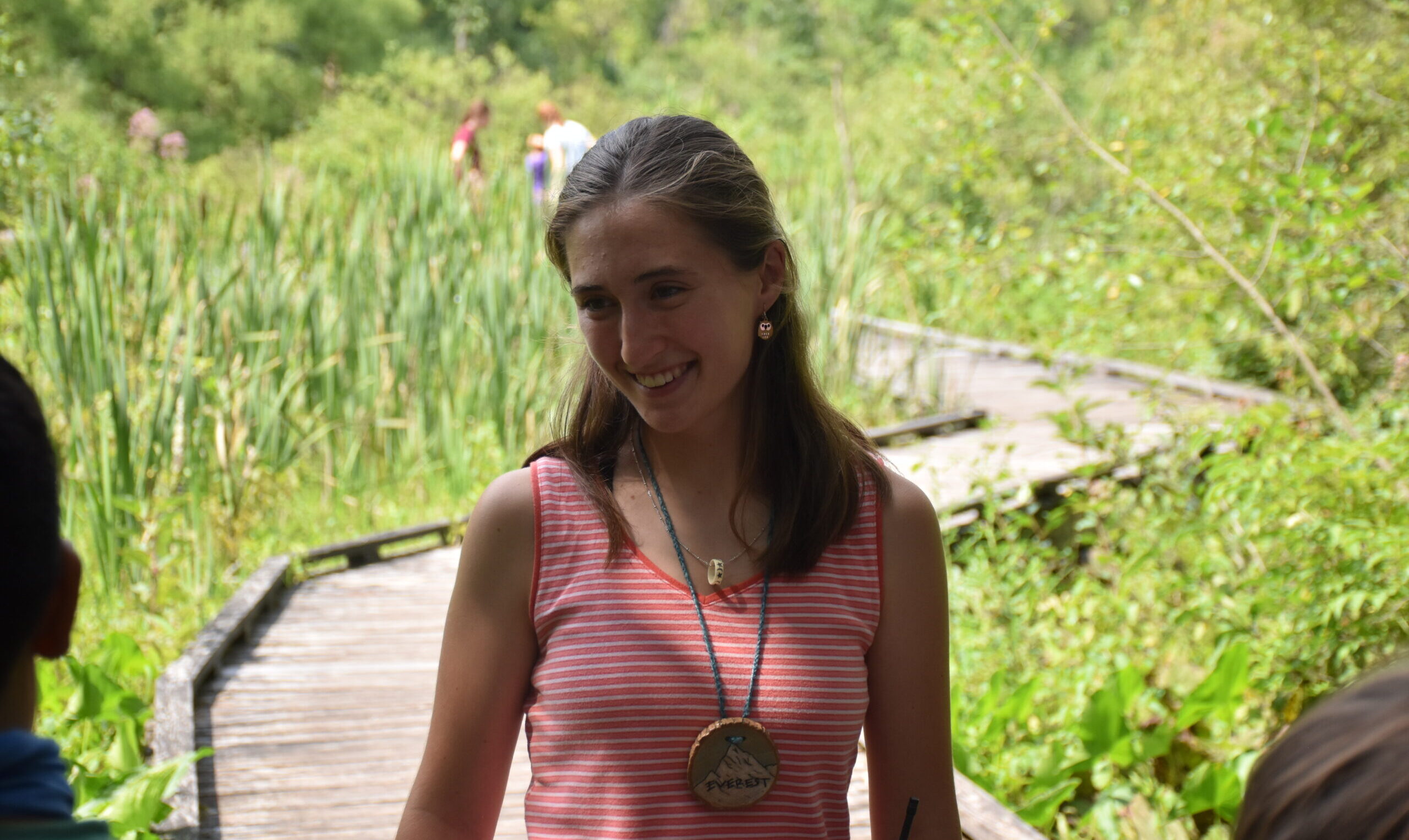 Sophia posing on a boardwalk that winds through a wetland