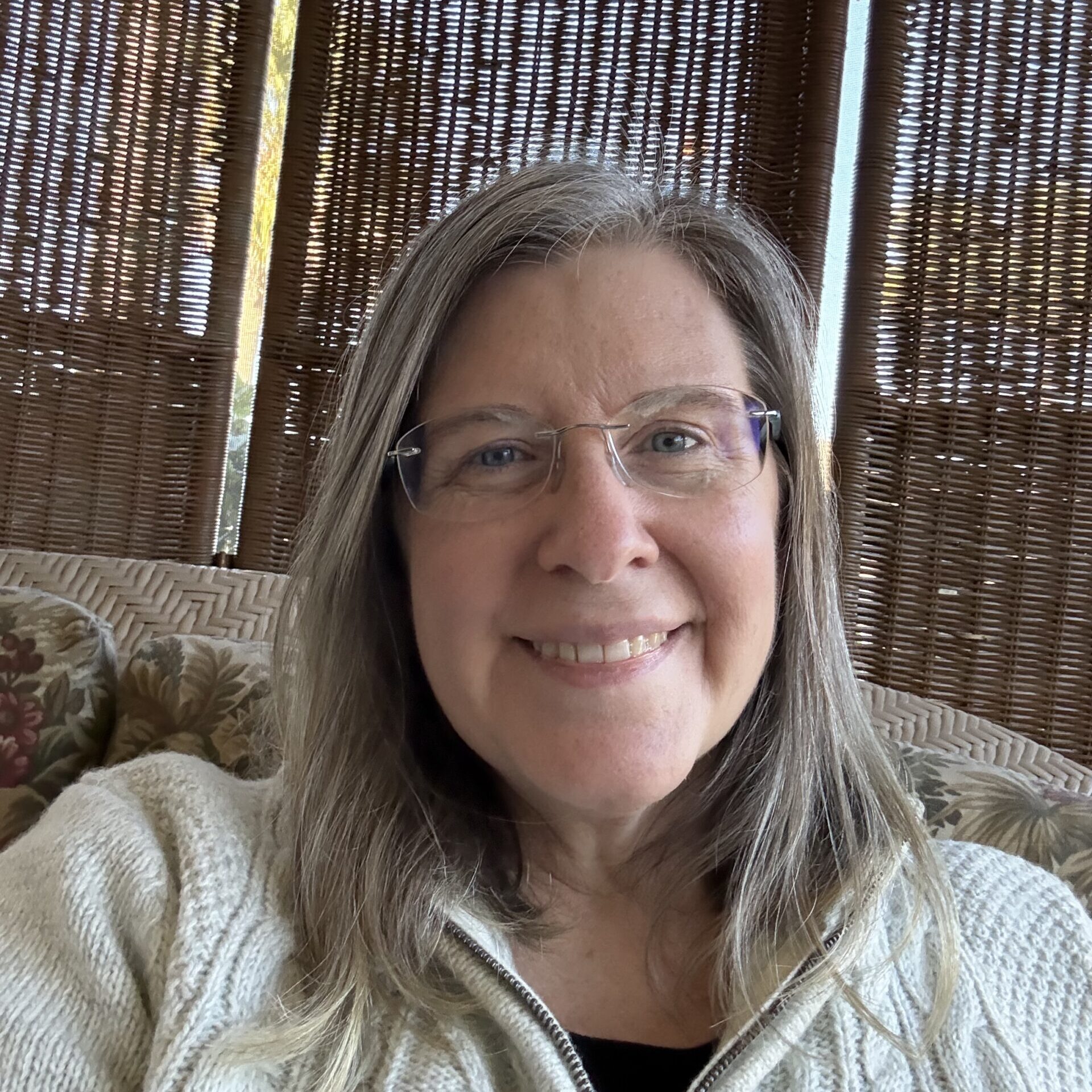 Monica sitting on a couch in front of some wicker screens.