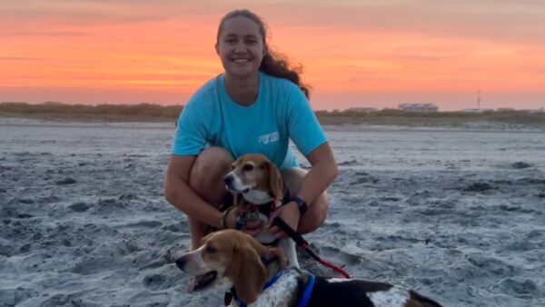 Meredith and her beagle on the beach with a beautiful sunset in the background.