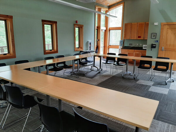 The Aerie Classroom set up with long tables forming a U shape and chairs on the outside of the U.