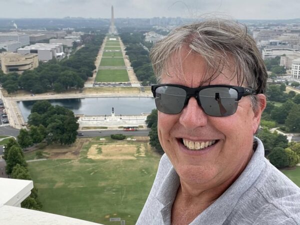 Mike taking a selfie from the top of the capitol dome with the National Mall in the background.