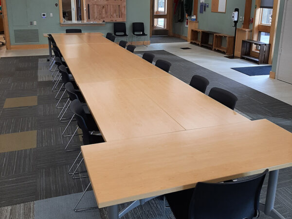 Hamer Classroom set up with on long conference table in the middle of the room and chairs on all sides of the table.