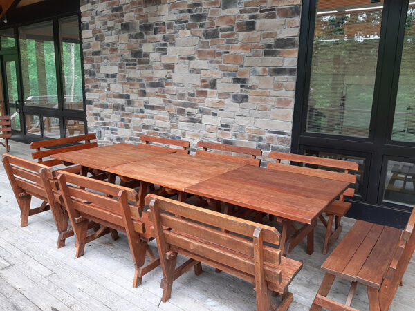 Hamer Deck set up with wooden tables pushed together to form a long conference-style table. There are wooden benches on all sides of the table.