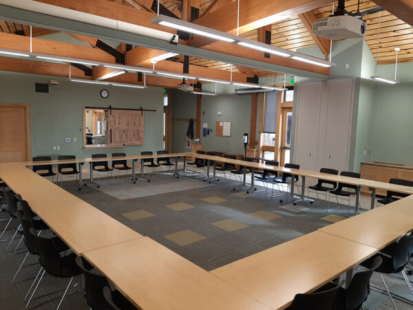 Hamer Classroom set up with long tables in a square and chairs on the outside of the square.