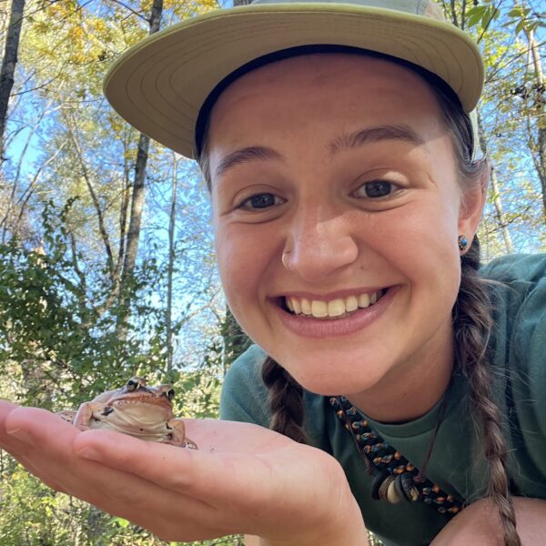 Maria holding a small frog in the palm of her hand.