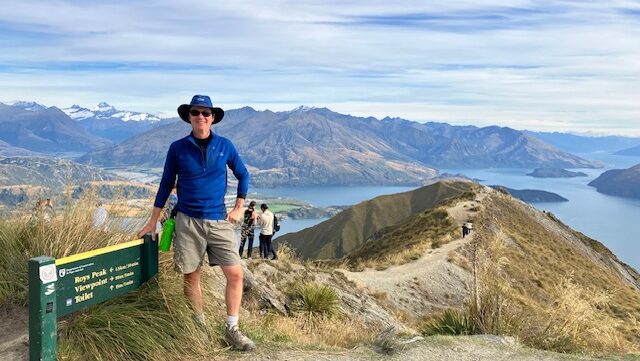 Jeff standing at an overlook at Roy's Peak with mountains and a lake behind him.