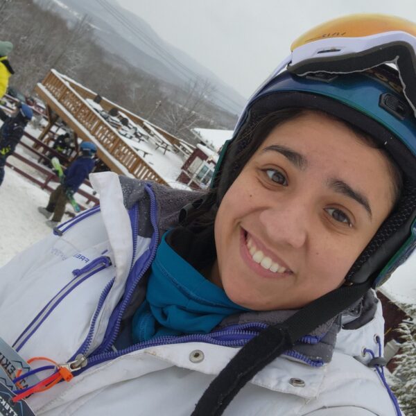 Raquel at a ski resort wearing a winter jacket and goggles.
