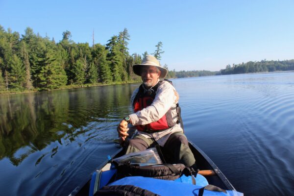 Bill kayaking in still water with conifers in the background.