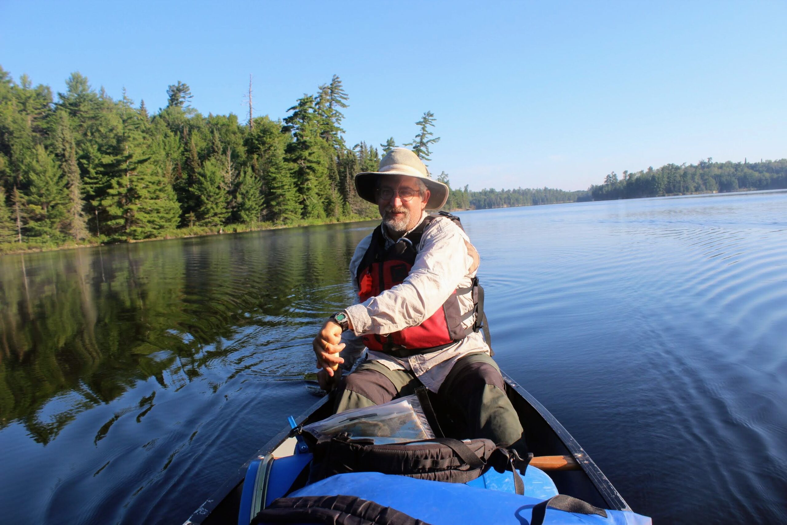 Bill kayaking in still water with conifers in the background.