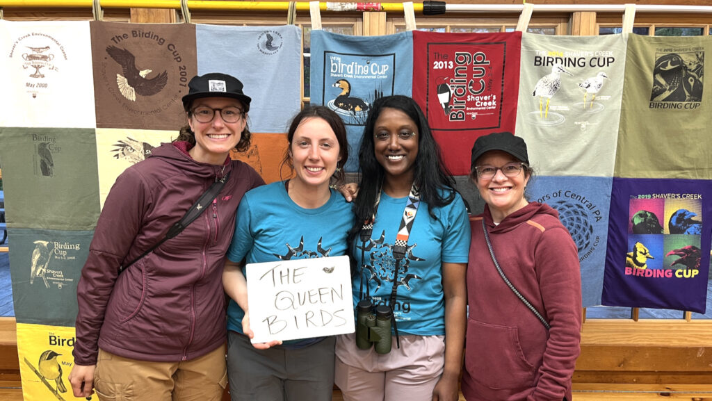 Four women pose with a sign that says "Queen Birds"