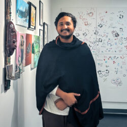 A man wearing a black cape stands in front of a whiteboard with handprints on it.
